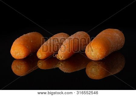 Group Of Four Whole Stale  Orange Stale Baby Carrot Baby Isolated On Black Glass