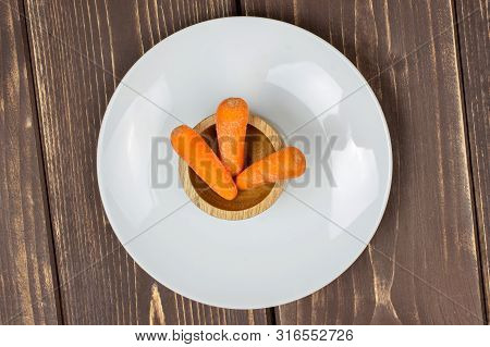 Group Of Three Whole Stale  Orange Stale Baby Carrot Baby On White Porcelain Plate In Wooden Cup Fla