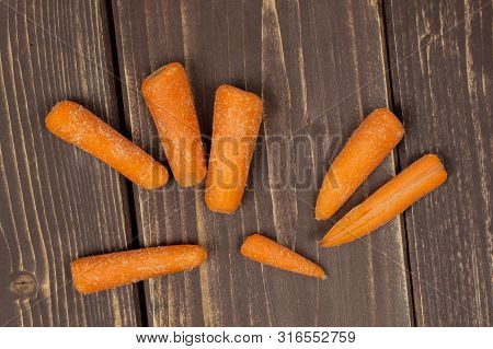 Lot Of Whole Stale  Orange Stale Baby Carrot Baby Flatlay Isolated On Brown Wood