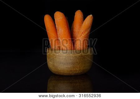 Group Of Four Whole Stale  Orange Stale Baby Carrot Baby In Wooden Cup Isolated On Black Glass