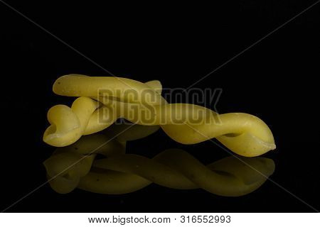 Group Of Two Whole Twisted Raw Pasta Gemelli Isolated On Black Glass