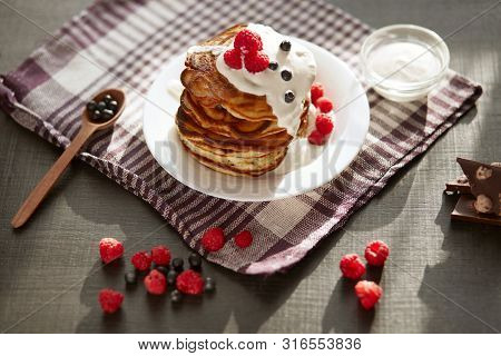 Top View Of Tasty Pancakes With Blueberries And Raspberries On Dark Brown Table, Cup Of Tea Or Coffe