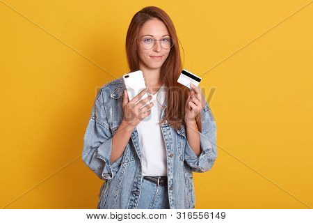 Horizontal Shot Of Adorable Smiling Woman Wering Casual Outfit Isolated Over Yellow Background, Hold