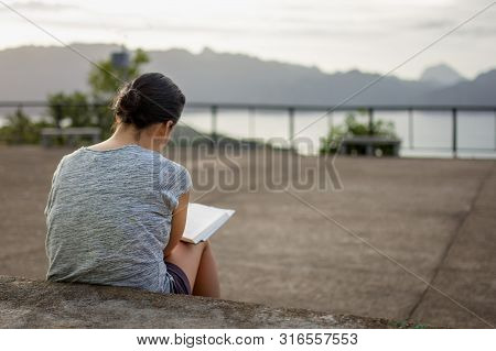 Rear View Of A Young Woman Wearing A Back Pack Looking Over A Cliff And Sea View.
