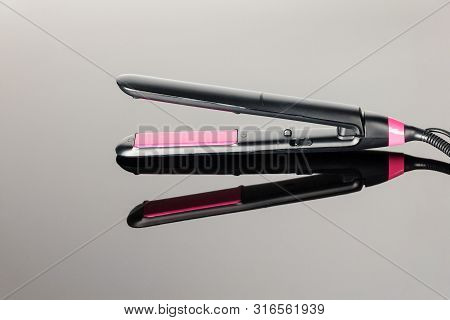 Electrical Hair Iron For Household On The Grey Mirror Background With Copy Space