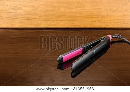 Electrical Hair Iron For Household On The Woody Mirror Background With Copy Space