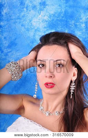 Dark-haired Girl In Exclavant Earrings And A Necklace On An Abstract Background.
