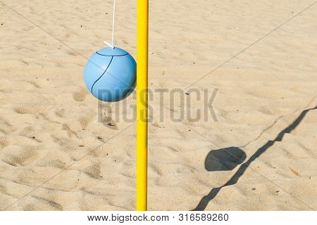 A Blue Ball And Yellow Pole On The Beach For Playing Tetherball.