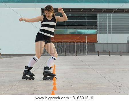 Woman Skating In The Street With Inline Skates Making Cones. Street Skating
