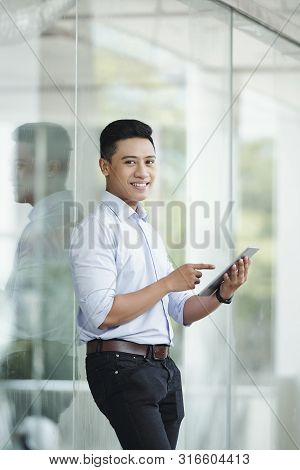 Positive Attractive Entreprenuer Pointing At Computer Screen In His Hands When Standing Outdoors