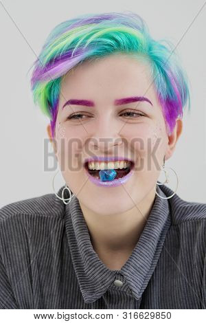 A Young Woman With Short Pixie Bob Haircut And Dyed Hair, Holds In The Mouth And In The Hands Gemsto