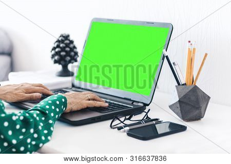 Close-up Of Hands Middle-aged Woman Typing On Keyboard Green Screen Laptop, Concrete Holder With Pen