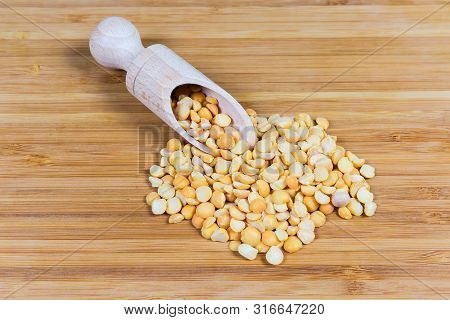 Ripe Split Peas Of Yellow Variety In Wooden Spice Spoon And Scattered Beside Her On A Bamboo Wooden 