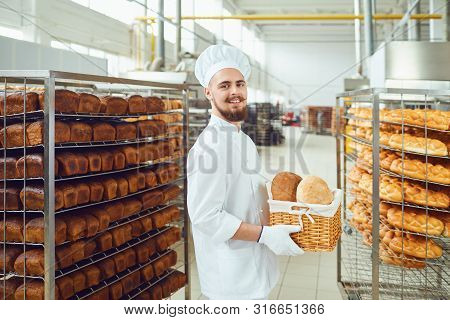 Bearded Baker Smiles Holding A Basket Of Bread At The Bakehouse