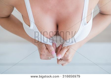 Sexy Woman Shows Off Her Big Silicone Breasts By Pulling Off Her White Top With Her Hands On A White