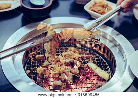 People Grilling Meat On A Smokeless Barbecue Grill In A Restaurant.