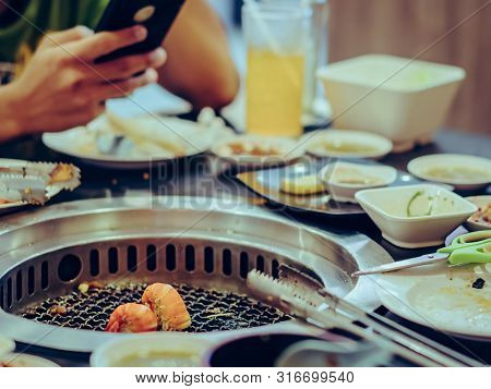People Grilling Meat On A Smokeless Barbecue Grill In A Restaurant. Selective Focus On Shrimps.