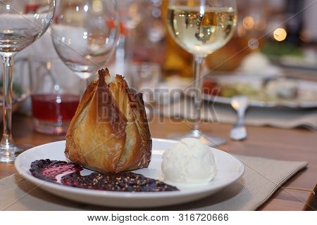 Dough Cake On A Plate With A Ball Of Ice Cream And Sauce Is On A Beautifully Served Table