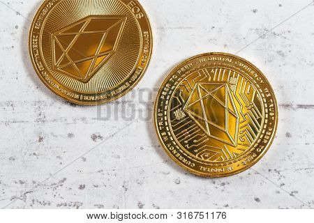 Top Down View, Detail Of Golden Commemorative Eos - Eosio Cryptocurrency - Coins On White Stone Boar