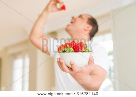 Middle age man eating straweberry at home