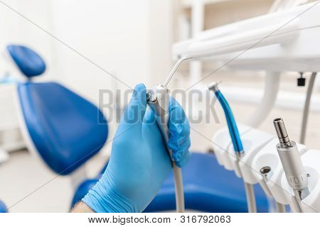 Close-up Hand Of Dentist In The Glove Holds Gun Dental Water And Air. . Office Where Dentist Conduct