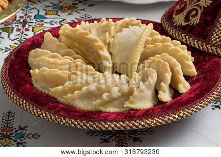 Festive tagine with traditional Gazelle Horns cookies on the table with embroidered table cloth
