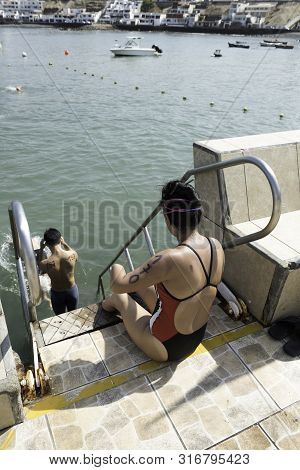 Young Swimmer Woman Who Has No Arms Or Legs Entering The Sea With The Competition Number Painted On 