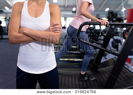 Mid section of woman standing with arm crossed in modern sports center. Sports Rehab Centre with physiotherapists and patients working together towards healing