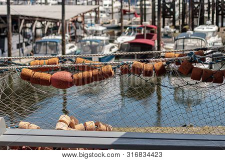 Fishing Net With Bouys Hang In Front Of Harbor Town