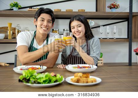 Portrait Of Cute Happy Couple In Aporn Jposting To Have Breakfast Decorated With Salad And Orange Ju