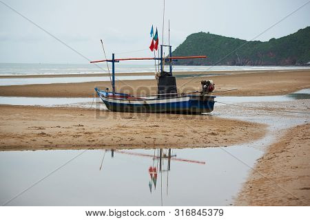An Old Blue Fisherman Boat At On The Beach In Cloudy Day