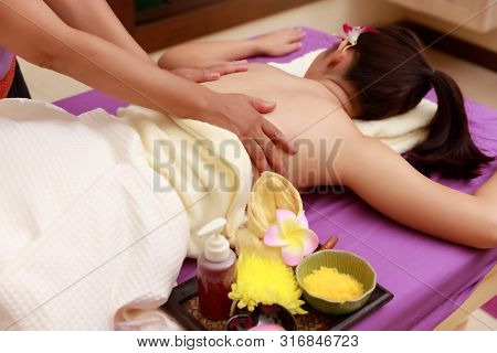 Asian Woman Enjoying A Salt Scrub Massage At Spa.