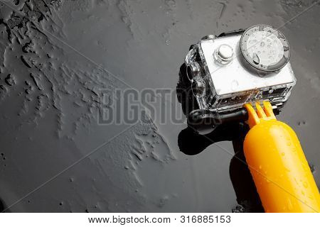 Action Camera In A Waterproof Box And A Buoy For Diving In Water Drops On A Black Background. Copy S