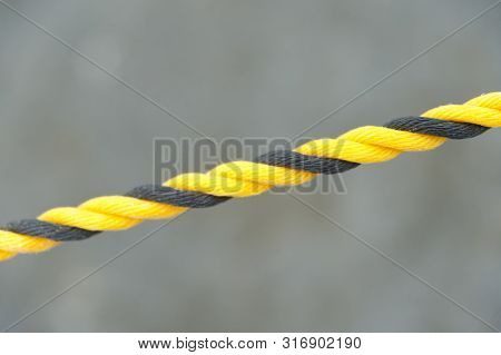 Yellow and black nylon rope. Nylon rope in diagonal direction. Isolated on blurred background. Close-up. Copy space.