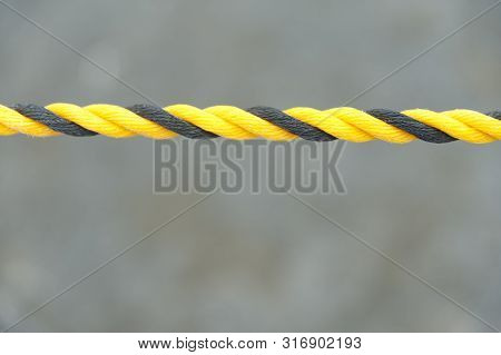 Yellow and black nylon rope. Nylon rope in horizontal direction. Isolated on blurred background. Close-up. Copy space.