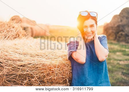 Great looking woman posing near rolled haystack at the countryside at sunny background