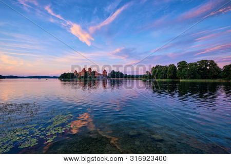 Trakai Island Castle in lake Galve, Lithuania on sunset with dramatic sky reflecting in water. Trakai Castle is one of major tourist attractions of Lituania