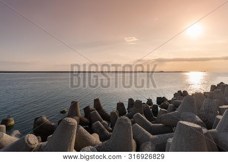 Tetrapod Breakwaters In Sea Water. Beautiful Sunset Seascape With Concrete Tetrapodes For Protect Co