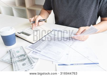 Man Using Calculator And Calculate Bills Receipt In Home Expenses Payments Costs With Paper Note, Fi