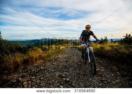 Mountain biking woman riding on bike in autumn mountains forest landscape. Woman cycling MTB flow trail track. Outdoor sport activity.