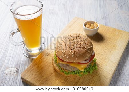 Burger With Beef Patty, Salad, A Slice Of Tomato And Cheese, Onions And Sauce With Paprika In A Gril