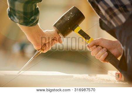 Closeup Of Unrecognizable Carpenter Hitting Nail With Hammer While Working In Joinery, Copy Space