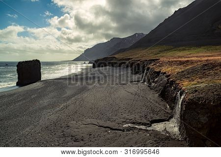 Small Waterfall In A Black Beach In Laekjavik Bay, Iceland