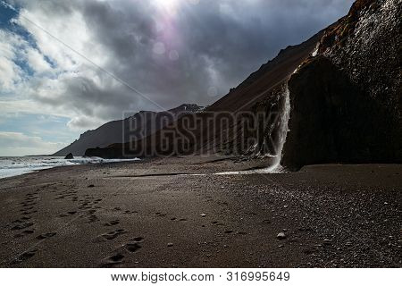 Waterfall In A Black Beach In Laekjavik Bay, Iceland