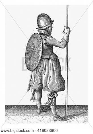 The exercise with shield and spear: the soldier standing with the spear resting on the ground next to the right foot, vintage engraving.