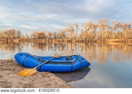 inflatable packraft (one-person light raft used for expedition or adventure racing) with a paddle on a lake shore in Colorado, early spring scenery