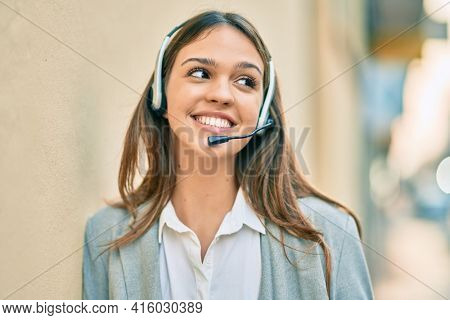Young latin call center aget girl smiling happy using headset at the city.