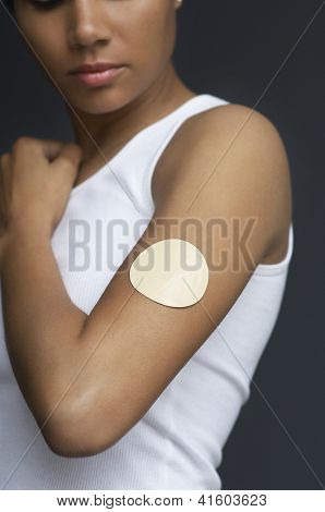 Mujer afroamericana con el parche de nicotina en el brazo