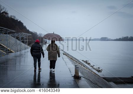 Belgrade, Serbia - January 31, 2016: People, Couple, Walking With Umbrellas Near The Danube River On