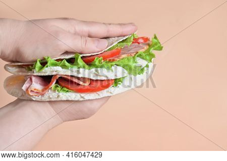 Italian Street Food. Piadina With Ham, Cheese And Tomatoes Close-up View. Hands Holding Stack Of Pia